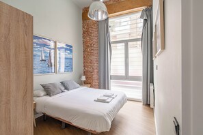 Ein modernes Schlafzimmer mit einem großen Bett, einer Ziegelwand und einem Fenster mit Vorhängen.