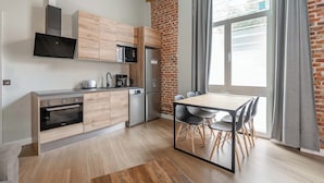 Eine moderne Küche mit Ziegelwand, Holzschränken, einem Edelstahlkühlschrank und einem Essbereich mit Tisch und Stühlen.