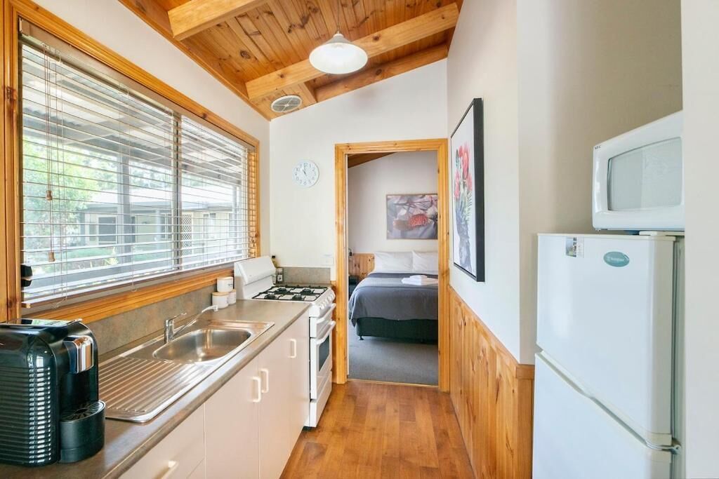 Una cocina compacta con estufa, lavamanos y microondas.