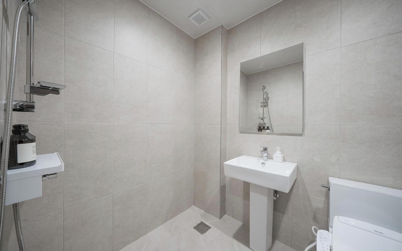 A modern bathroom with a shower, a sink, and a toilet.