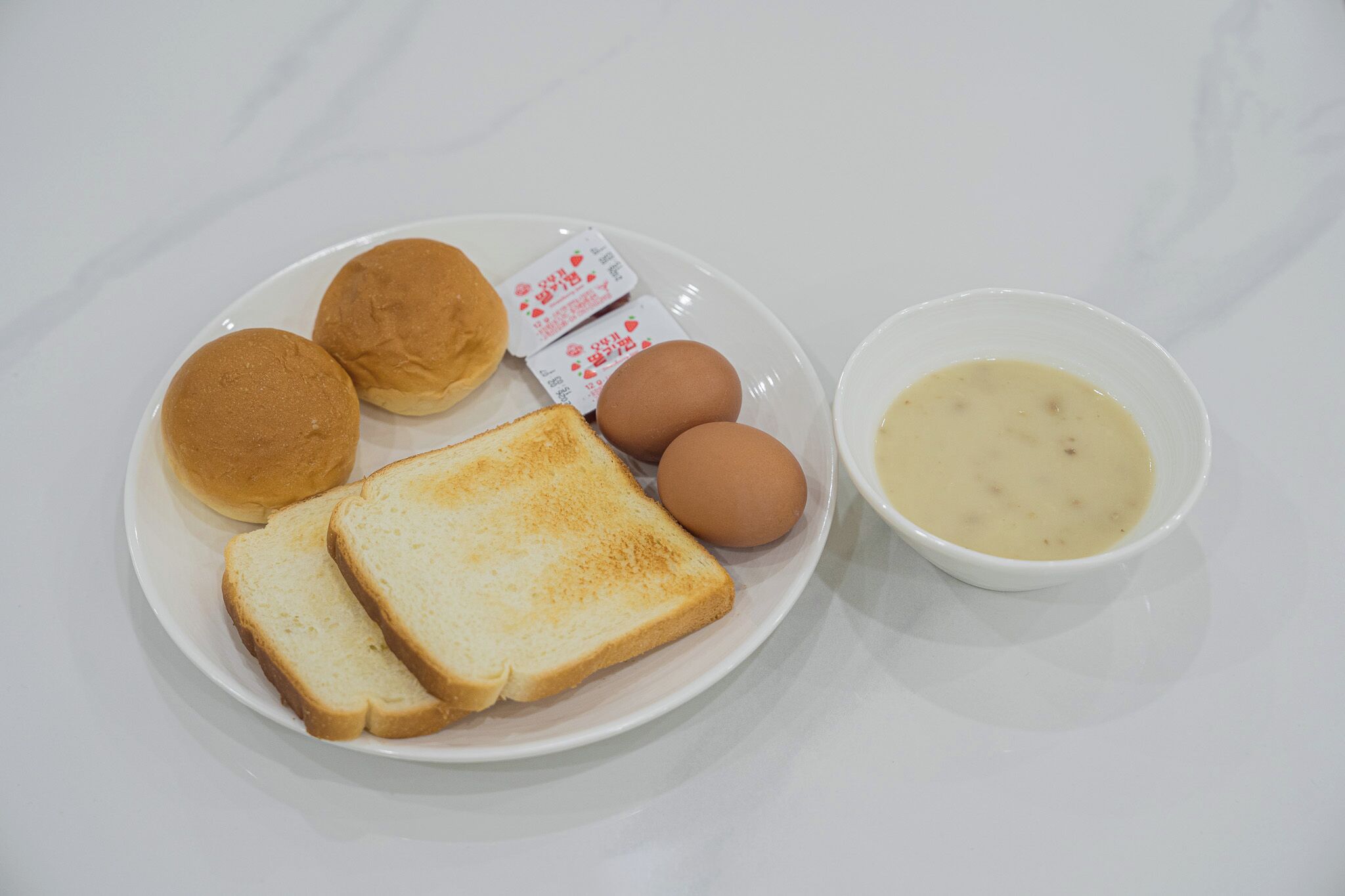 A plate with toast, eggs, and a bowl of soup.