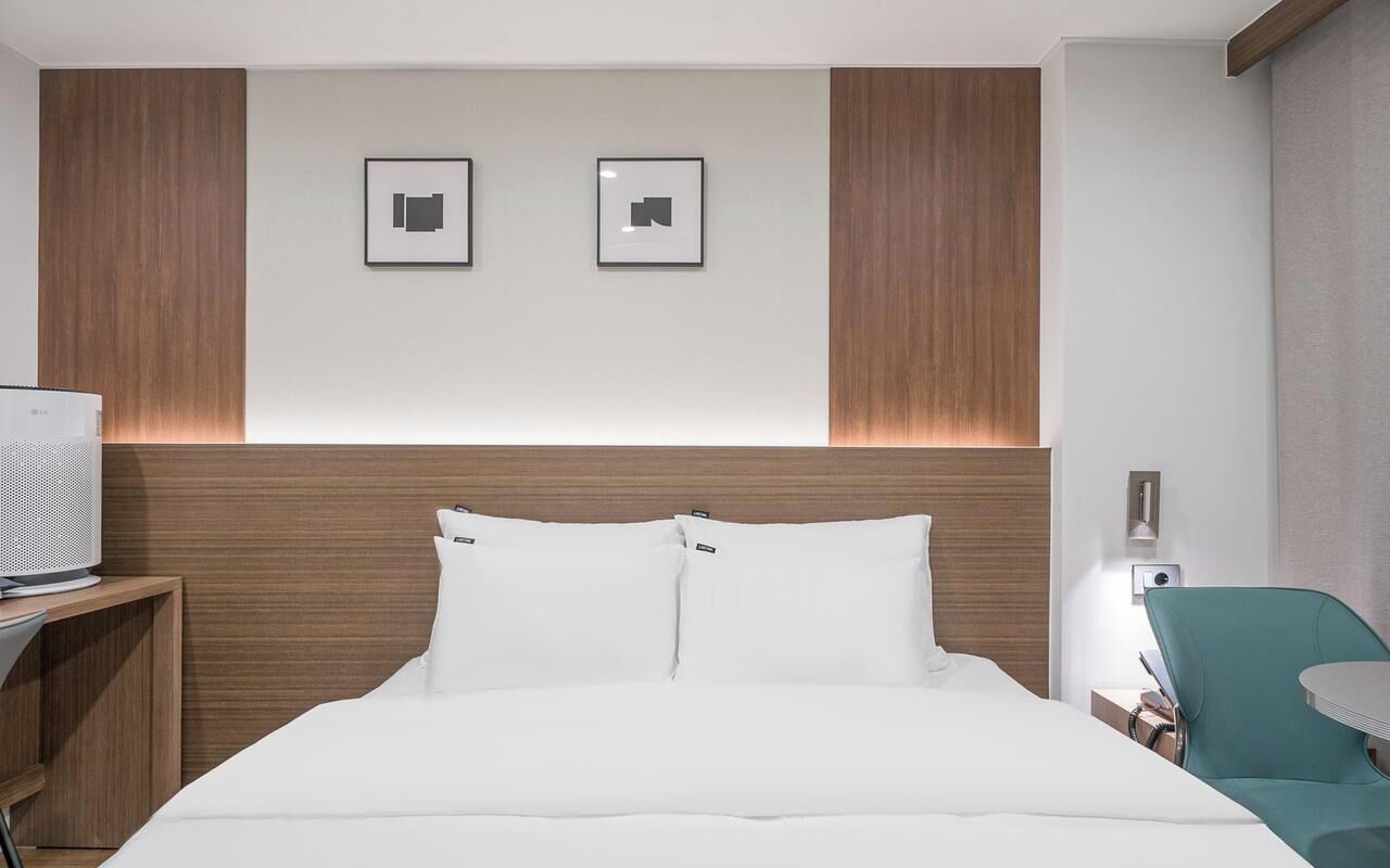 Una habitación de hotel con cama, televisor, escritorio y silla.