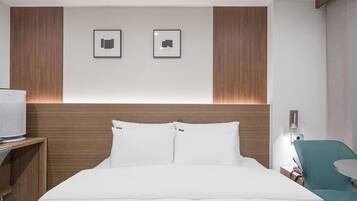 Una habitación de hotel con cama, televisor, escritorio y silla.