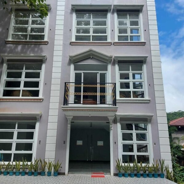 A multi-story building with a central entrance, large windows, and a balcony with a railing. - Hotel NaeR (Romblon)