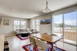 Un vaste espace de vie comprenant une grande table à manger, un canapé et une table basse. De grandes fenêtres offrent une vue sur l’extérieur.