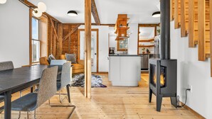 Ein modernes Interieur mit Essbereich, einer Couch, einem Kamin und einer Küche im Hintergrund.