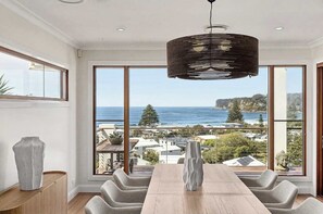 A dining area with a view of the ocean and a statue. - Glendalough by Coast Hosting (North Avoca)