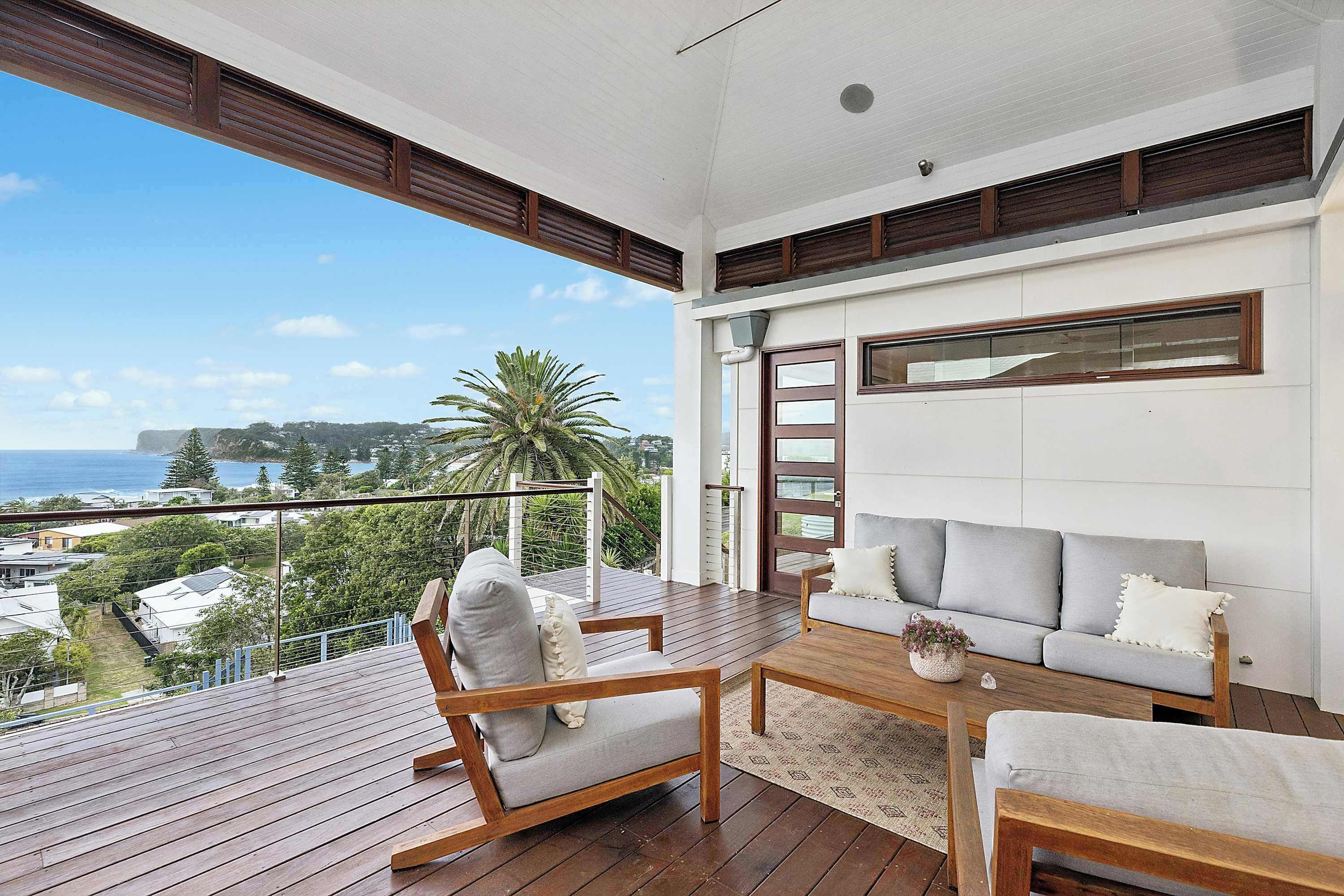 A balcony with wooden flooring, a sofa, and a chair.