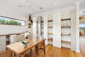 A modern dining area with a wooden table, chairs, and a ceiling fan. - Glendalough by Coast Hosting (North Avoca)