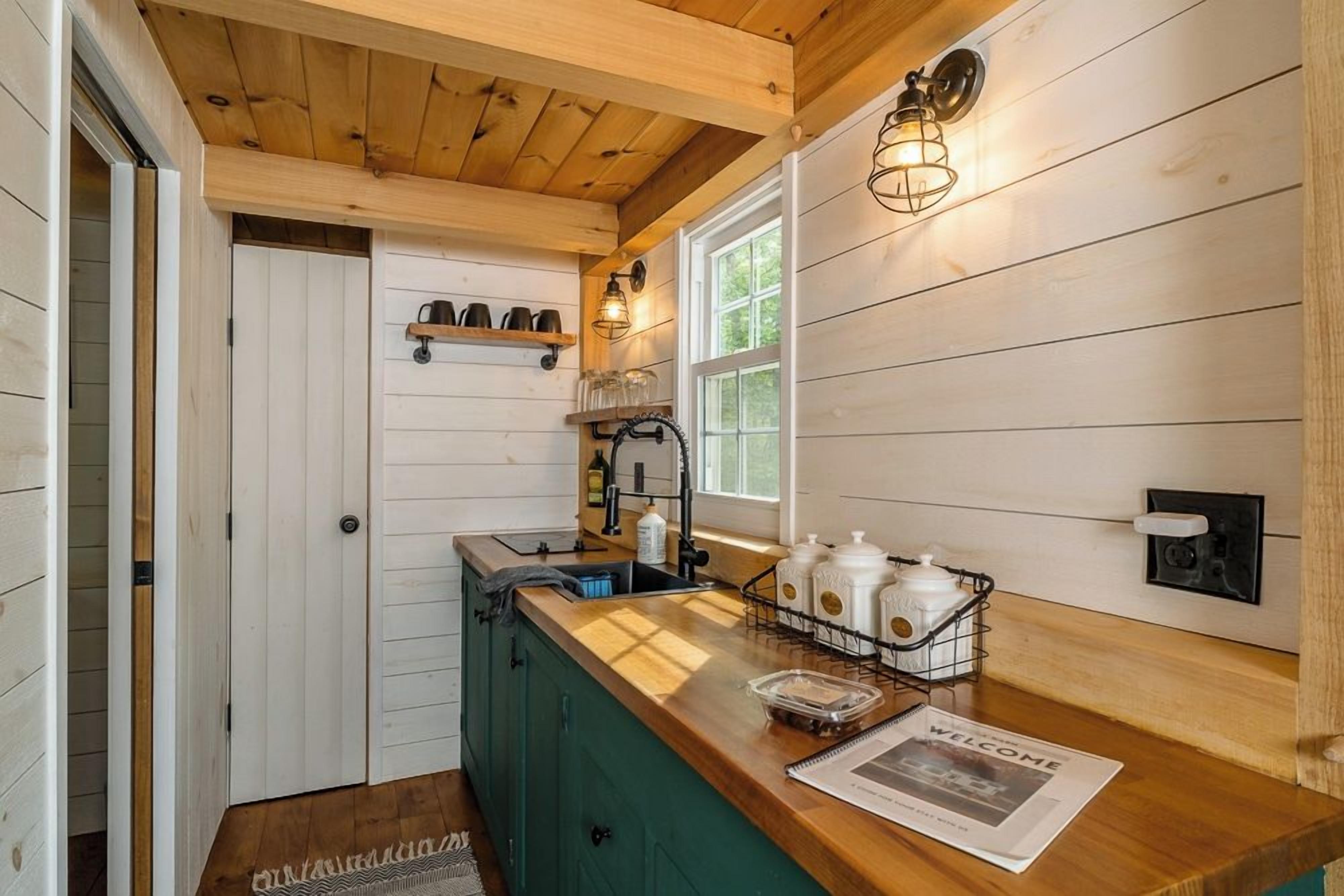 A kitchen with wooden cabinets, a sink, a window, and a welcome mat.