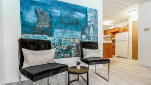 Un soggiorno moderno con due poltrone in velluto nero, un piccolo tavolino e un grande quadro astratto appeso al muro.