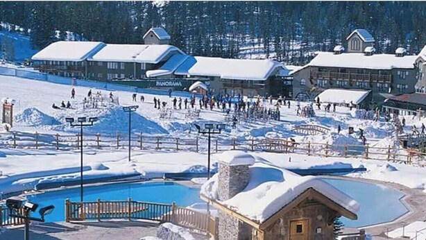 Una località sciistica con area piscina, impianti di risalita e chalet.