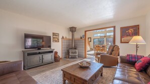 Sala de estar con televisión, sofá, mesa de centro, chimenea y comedor.