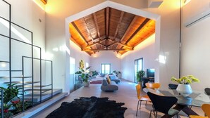 Un vaste espace de vie doté d’un haut plafond, de meubles modernes et d’un grand tapis noir.