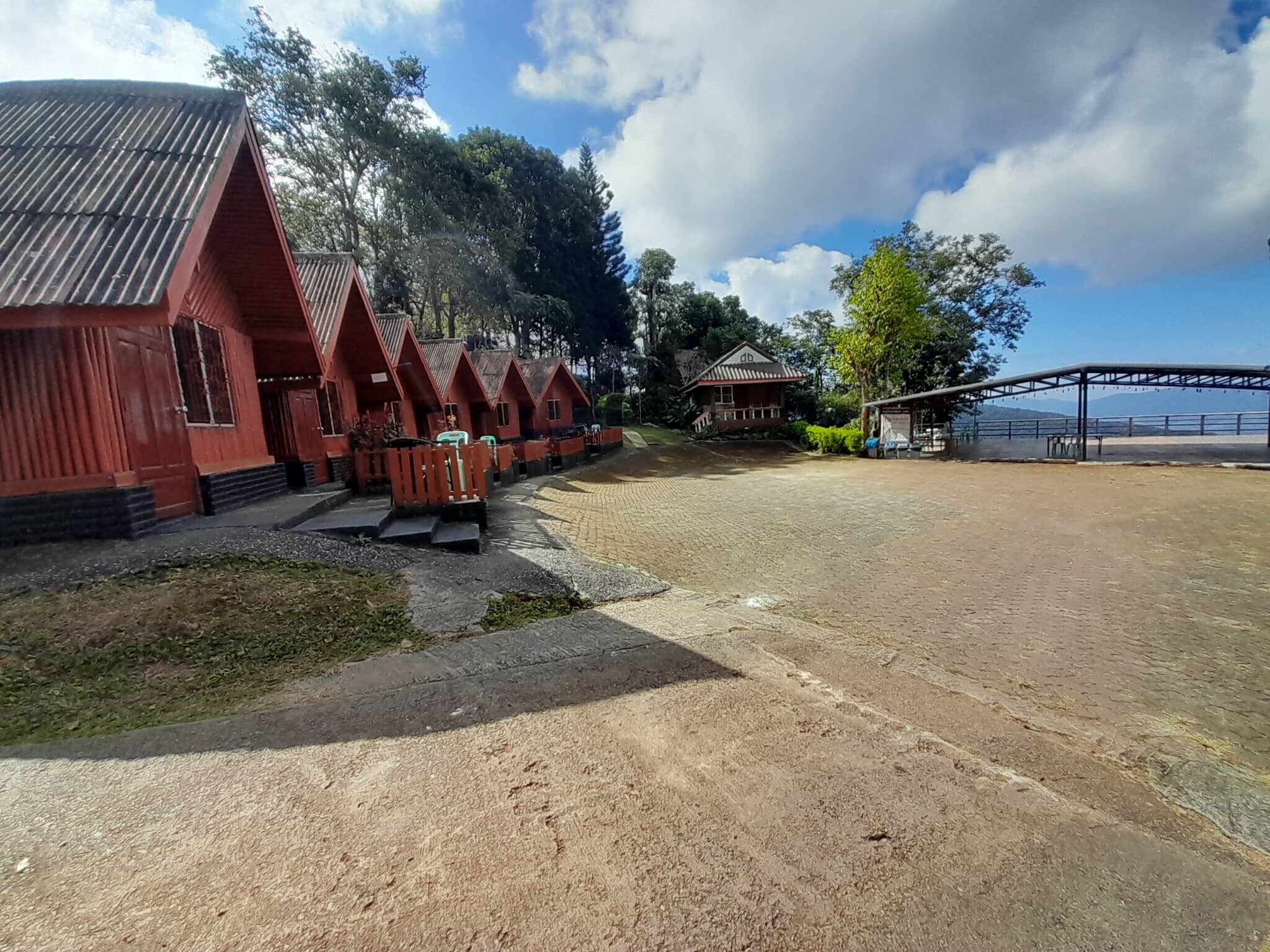 A row of red-roofed cabins with a paved area in front.