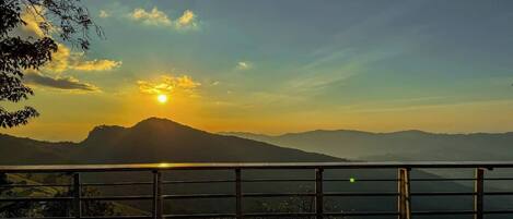 Une terrasse offrant une vue sur une chaîne de montagnes au coucher du soleil.