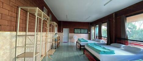 A room with two beds, a fan, and a door.