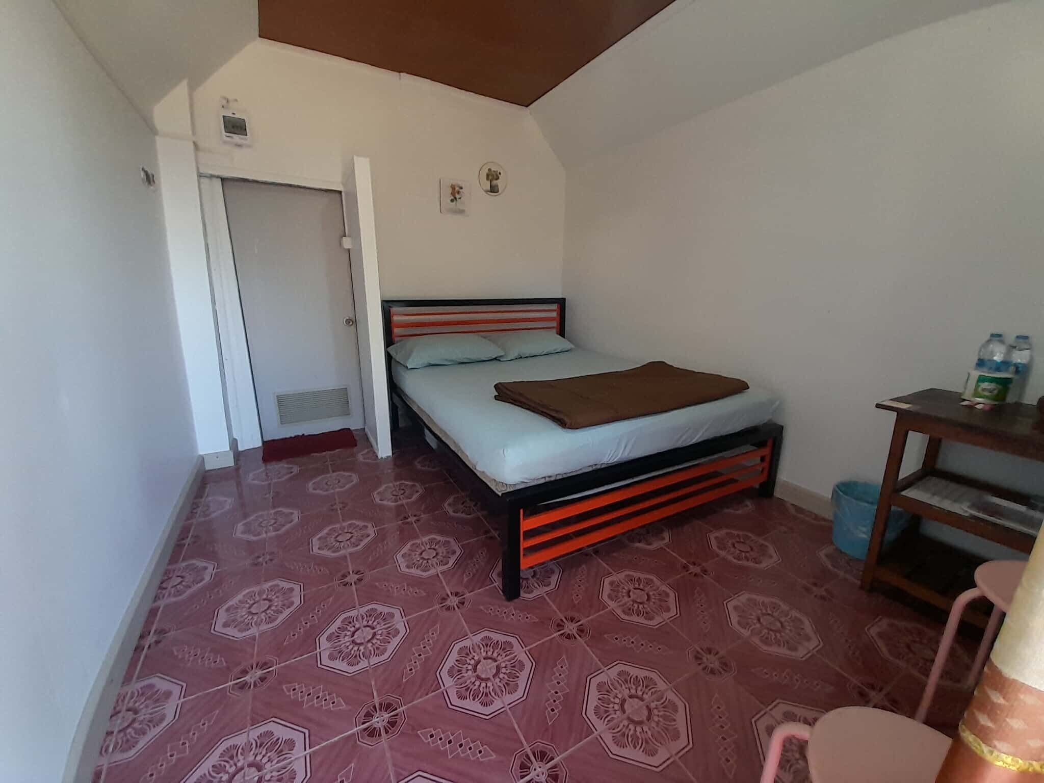 A small, single-room accommodation with a bed, a desk, and a chair.