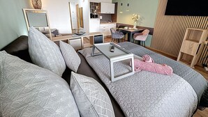 A modern living room with a sofa set, a coffee table, and a dining area with chairs. - Nice apartment for 3 guests with WIFI, pool, TV, terrace and panoramic view (Sankt Englmar)