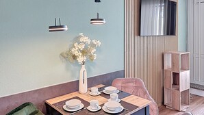 A dining area with a table set for four, a vase with flowers, and a modern light fixture. - Nice apartment for 3 guests with WIFI, pool, TV, terrace and panoramic view (Sankt Englmar)