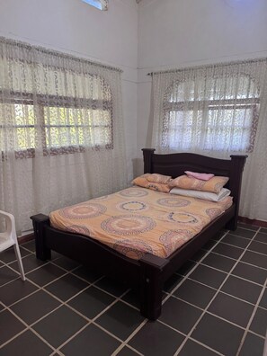 Un dormitorio con cama, cortinas y una silla.