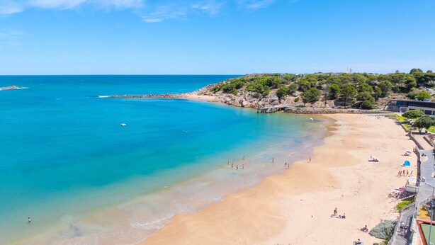 A beach with clear turquoise waters, a sandy shore, and a rocky hill with trees. - Yesterdaze - 5 North Tce, Port Elliot (Port Elliot)