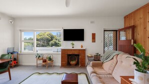 A living room with a fireplace, a television, and a view of trees through a window. - Yesterdaze - 5 North Tce, Port Elliot (Port Elliot)