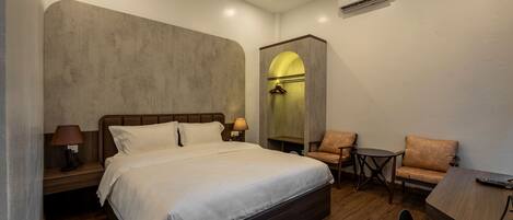 Une chambre à coucher avec un grand lit, un bureau, une chaise et une petite table.