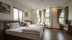 A hotel room with two beds, a desk, and large windows. - Odyssey Hotel 2 (Ha Giang 1)