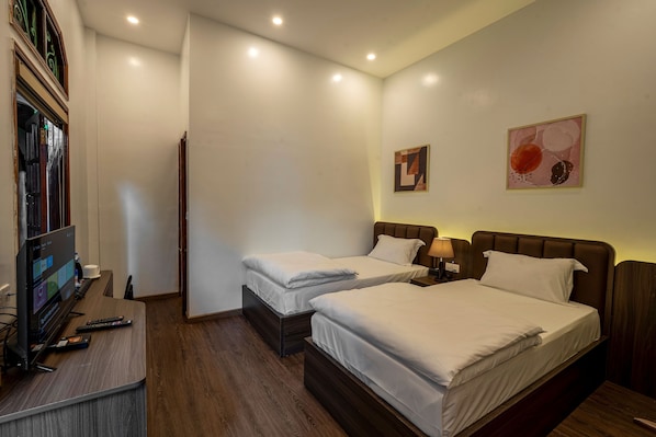 A hotel room with two beds, a TV, and a desk with a remote control. - Odyssey Hotel 2 (Ha Giang 1)