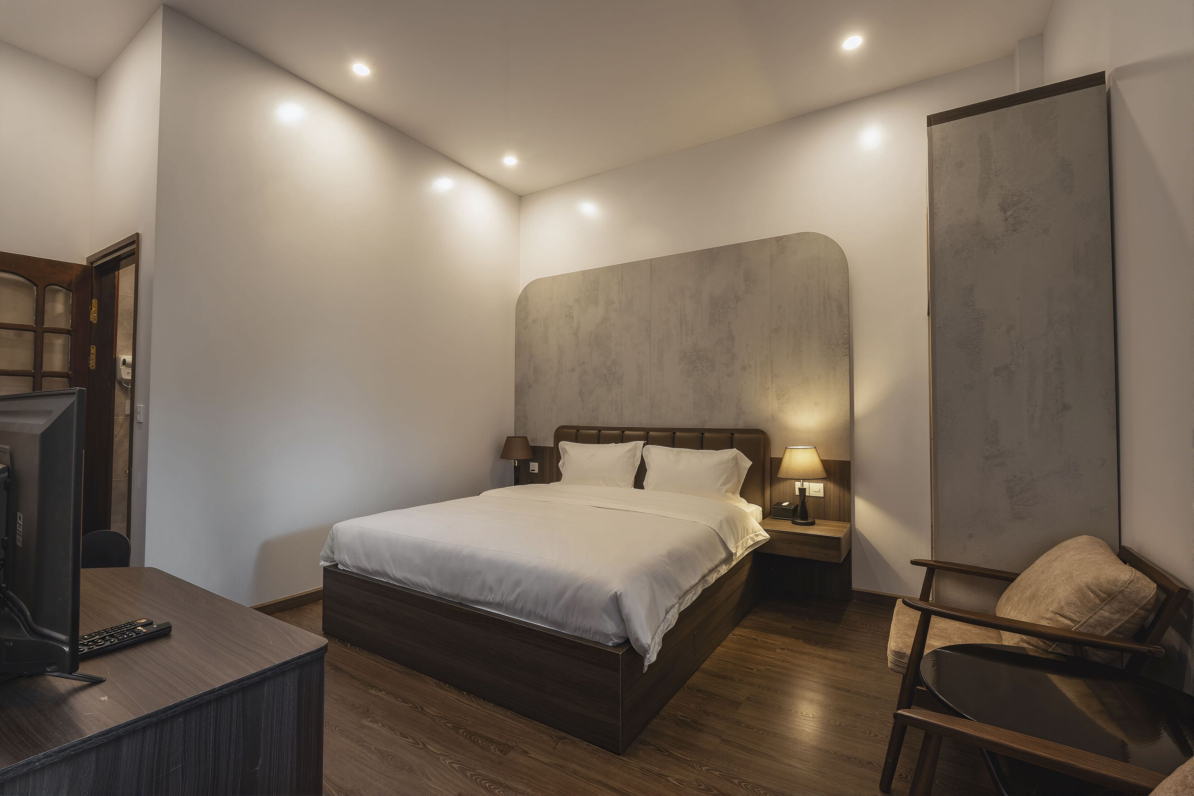 Um quarto moderno com uma cama grande, mesas de cabeceira, uma escrivaninha e uma cadeira.