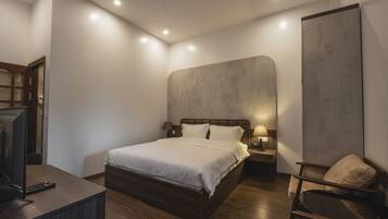 Um quarto moderno com uma cama grande, mesas de cabeceira, uma escrivaninha e uma cadeira.