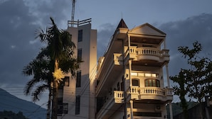 A multi-story hotel with a balcony on the second floor, a sign for 'ODYSSEY HOTEL', and a palm tree in front. - Odyssey Hotel 2 (Ha Giang 1)
