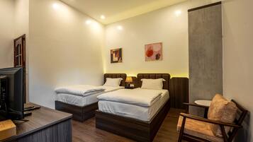 A hotel room with two beds, a desk with a computer, a chair, and artwork on the walls.
