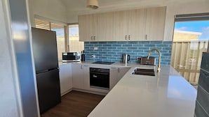A modern kitchen with a central island, built-in appliances, and a view of the outside.