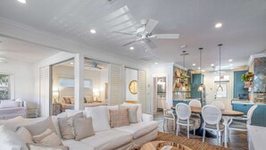 A spacious living room with a sofa, chairs, a dining table, and a kitchen area with blue cabinets. - Beach House on the Beach for 8 People With Jacuzzi (Hollywood)