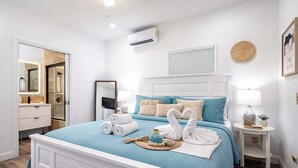 A bedroom with a bed, bedside tables, a mirror, and a wall-mounted air conditioner. - Beach House on the Beach for 8 People With Jacuzzi (Hollywood)