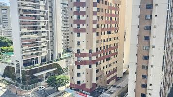 Um edifício alto com vários andares, uma área de estacionamento e uma rua com carros.
