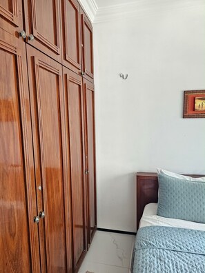 Quarto com uma cama, um guarda-roupa de madeira e um quadro na parede.
