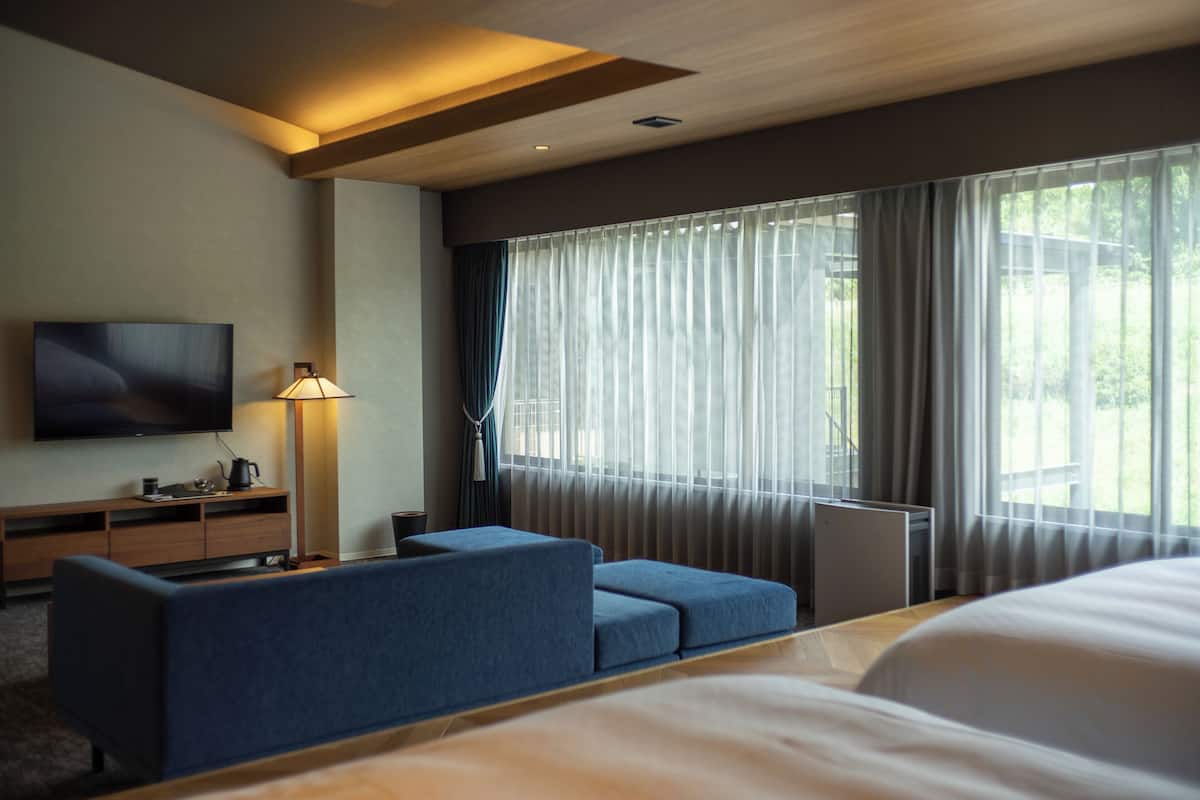 Une chambre d’hôtel avec un lit, une télévision, un bureau et une fenêtre avec des rideaux.