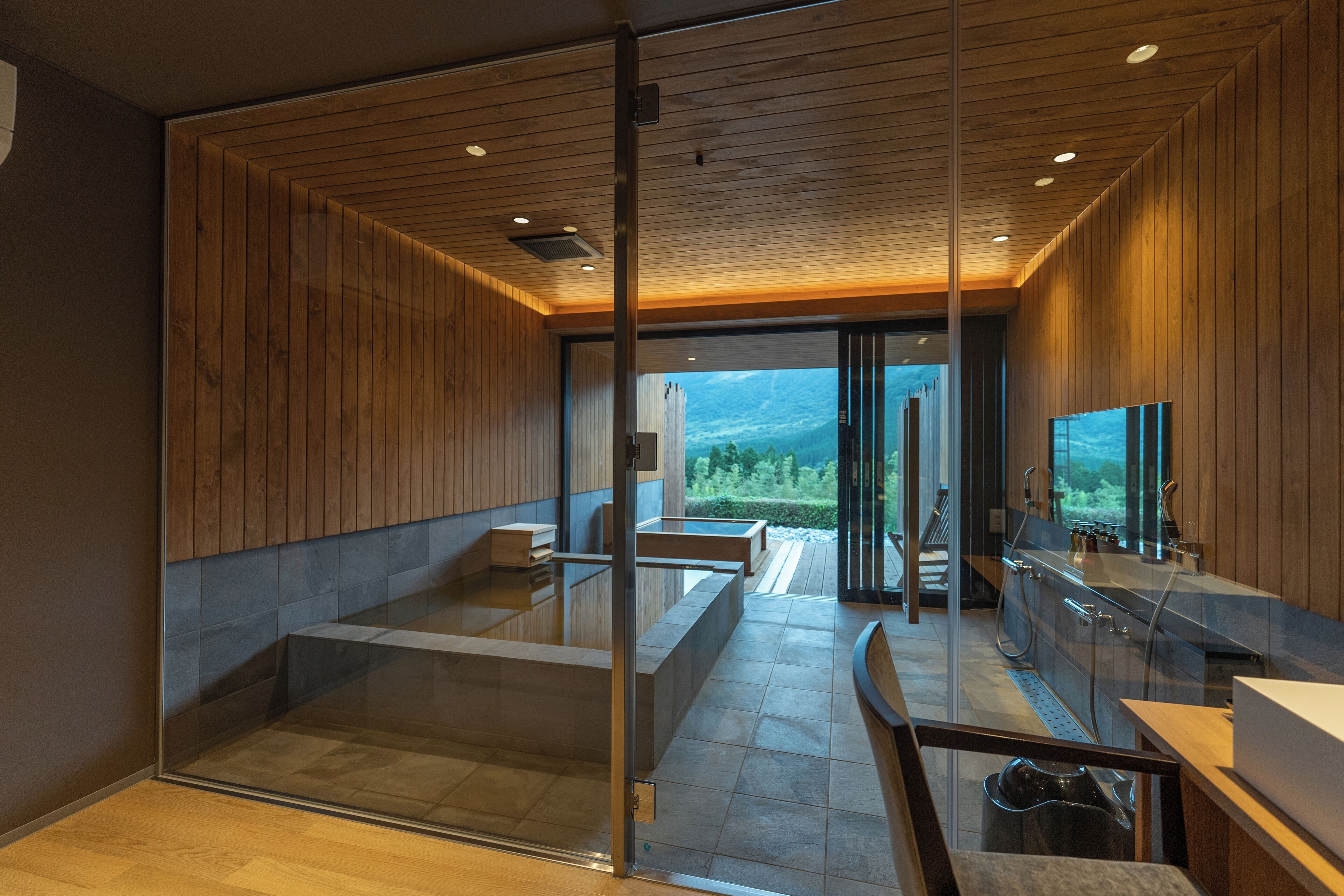 A modern interior with wooden paneling, a glass partition, and a view of a mountainous landscape.