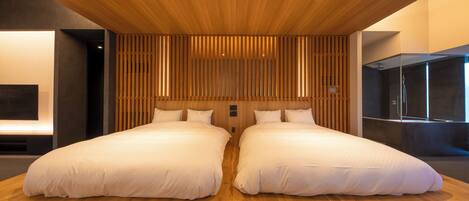 A modern hotel room with a large bed, wooden ceiling, and a TV mounted on the wall.