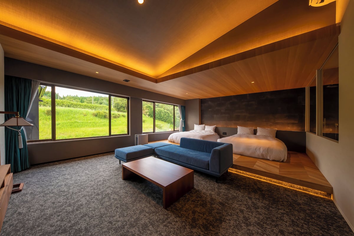 Une chambre moderne avec un grand lit, un canapé bleu et une table basse en bois.