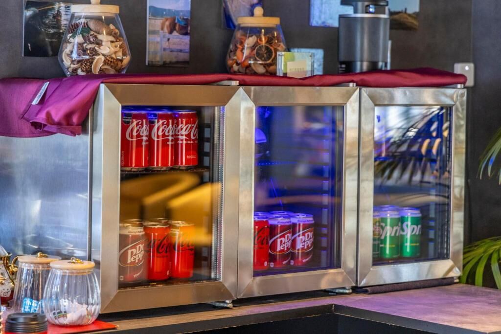 Jääkaappi, jonka hyllyt ovat täynnä Coca-Cola- ja Dr. Pepper -limsapulloja.