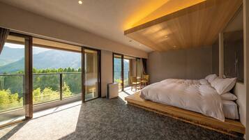 A modern bedroom with a large bed, a small table, and a chair, large windows with a mountain view, and a wooden ceiling.