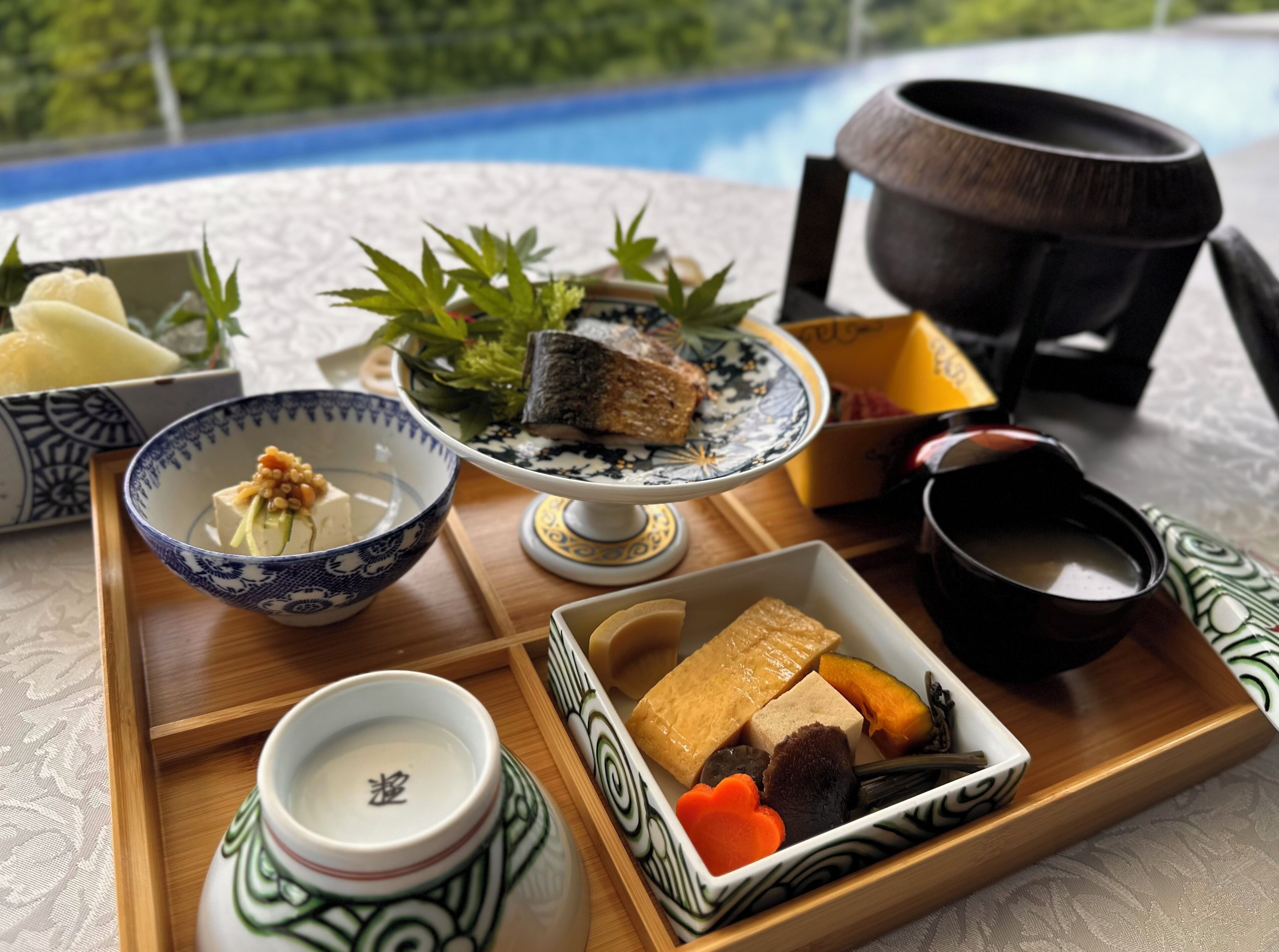 A tray with various Japanese dishes, including sushi, pickled vegetables, and a bowl of soup.