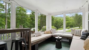 A covered porch with a bench, seating area, and a table. - Ski Oasis w/ Hot Tub near Killington & Woodstock (Bridgewater)