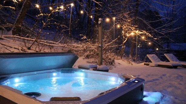 A hot tub surrounded by snow, with lounge chairs and string lights. - Ski Oasis w/ Hot Tub near Killington & Woodstock (Bridgewater)