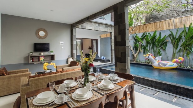 Un espace repas moderne avec vue sur la piscine, un téléviseur à écran plat et une table à manger dressée pour six personnes.