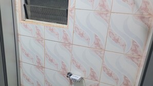 A shower area with a Protex shower head, a window, and a green mat on the floor.